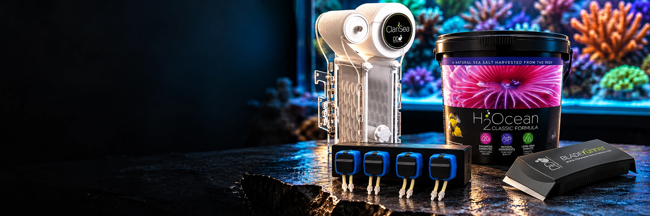 D-D Produktmix mit ClariSea Filter, H2Ocean Dosierpumpe, Classic Formula Meersalz und Bladerunner vor einem Korallenriff.